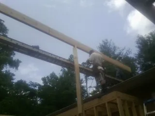 Carpenter setting a ridge beam over a new addition frame — Ice Dam Removal by Roofing Brothers in Keego Harbor