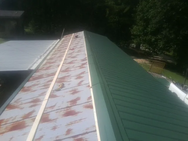 Old rusted panels beside newly installed green metal roofing — Wind Damage Roof Repair by Roofing Brothers in Keego Harbor