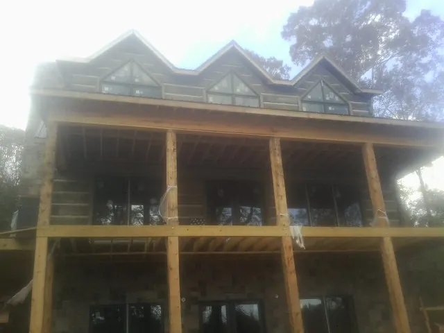 Dormers and porch framing on a large log home under construction — Roof Coating work by our crew in Keego Harbor