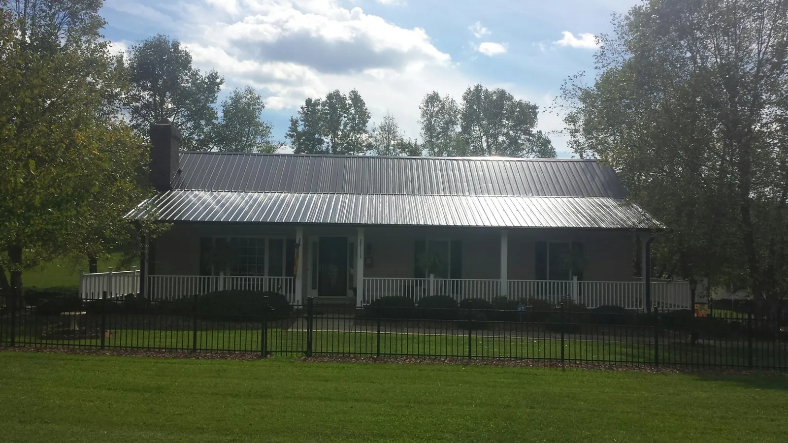 Gray metal roof on a brick ranch with a full width front porch — Gutter Guard Installation work by our crew in Keego Harbor