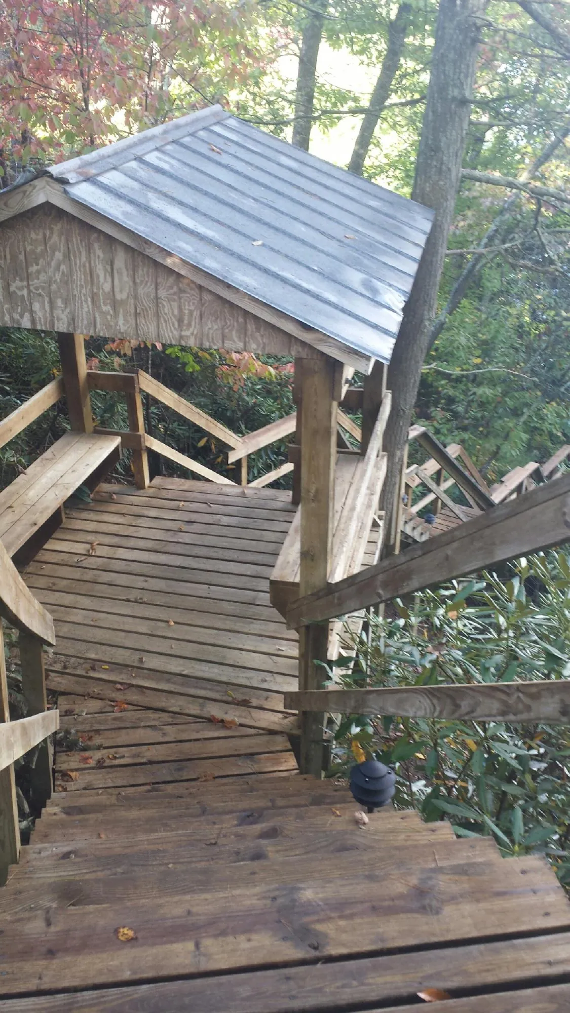 Metal roofed shelter over wooden steps on a wooded walkway — Skylight Repair & Installation work by our crew in Keego Harbor