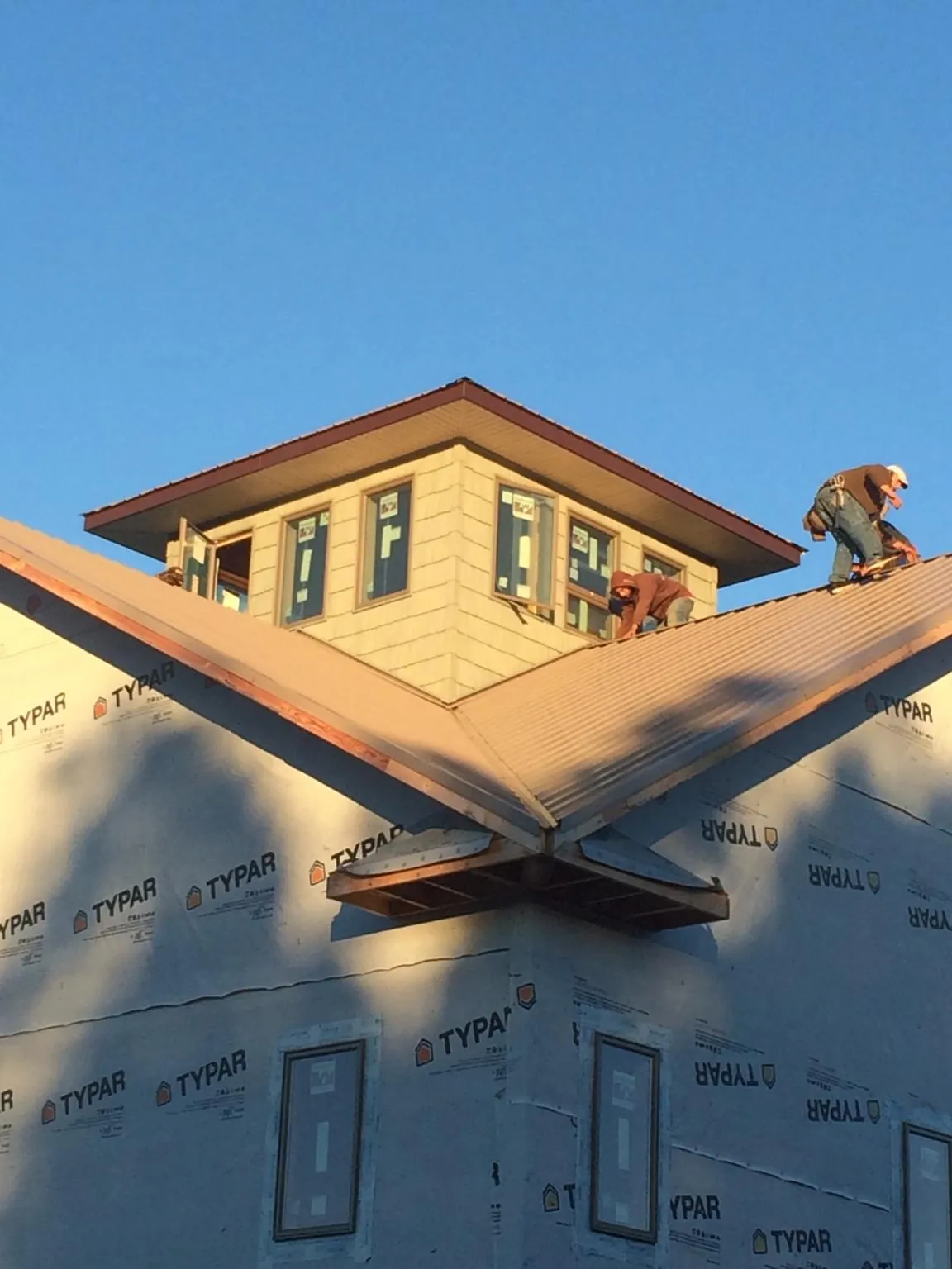 Roofers working around a rooftop cupola on a new metal roof at sunset — Roof Waterproofing in Keego Harbor by Roofing Brothers